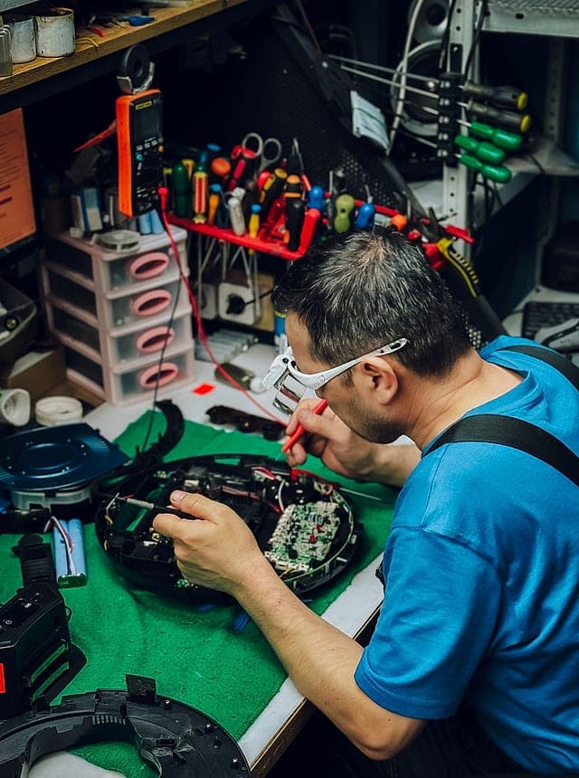 Kỹ thuật viên điện tử sửa board tại bàn nghề với đủ đồ nghề đo đạc